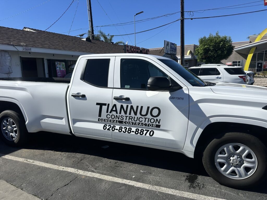 White Tiannuo Construction work truck with company branding and license plate parked in front of a job site house
